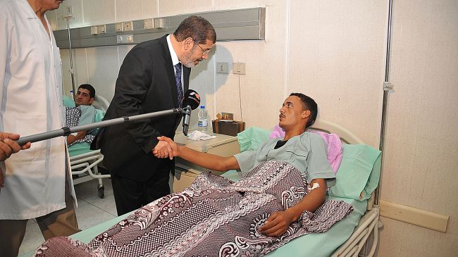 Egyptian President Mohamed Morsi (L) shakes hands with an Egyptian soldier who was wounded in an attack in Sinai during a visit to soldiers at a hospital in Cairo, August 7, 2012.
